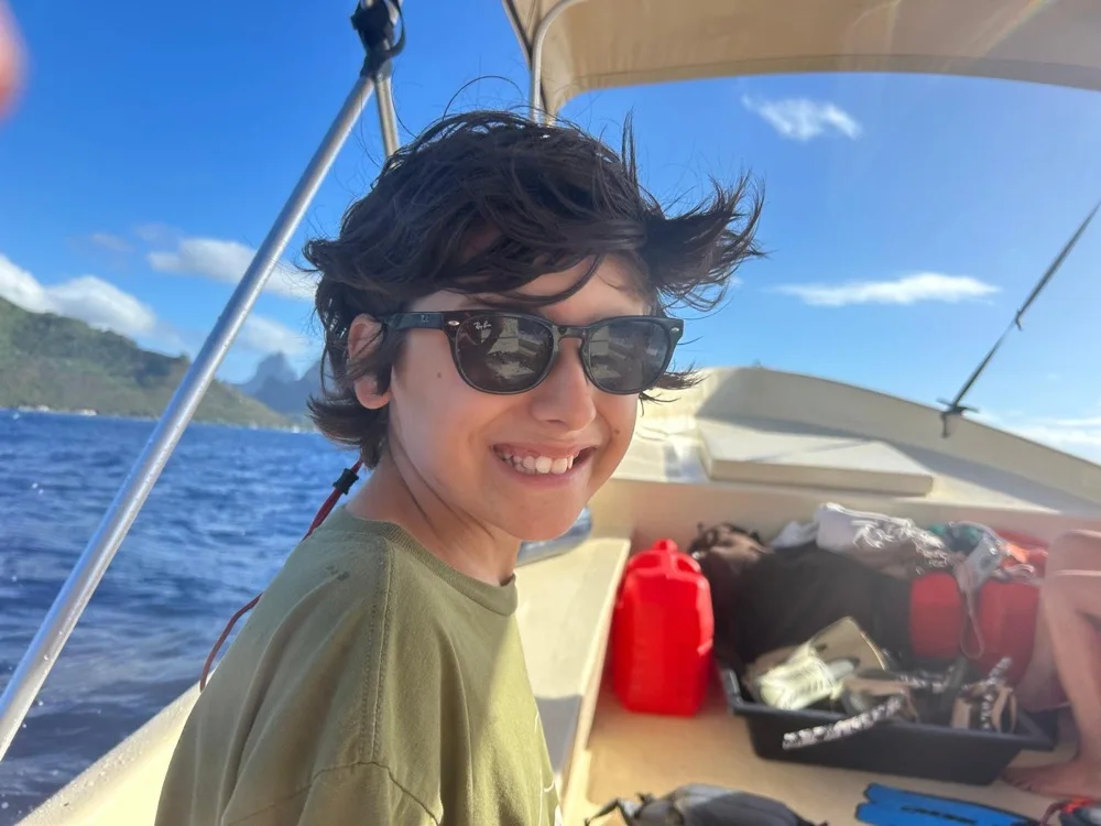 Samuel, lunettes de soleil, tout sourire sur un bateau